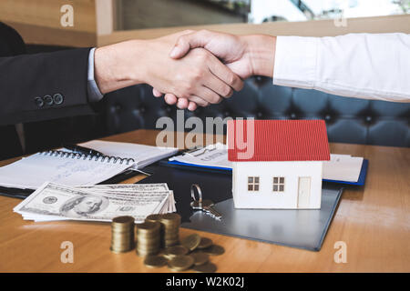 Immagine di successo del settore immobiliare, broker e client si stringono la mano dopo la firma del contratto approvato sotto forma di applicazione, riguardante il mutuo ipotecario di Foto Stock