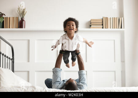 Felice african kid boy battenti in padri bracci sul letto Foto Stock