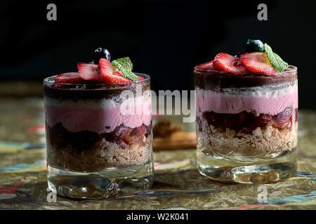 Mousse di biscotto, ciliegie, ananas e ricoperte di cioccolato ricoperto con una crema di cioccolato, mirtilli e fragole. Foto Stock