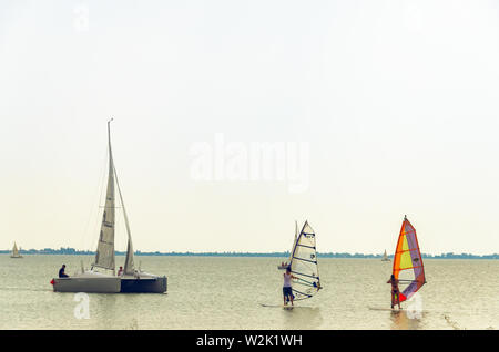 Podersdorf am See, Austria - 15 agosto 2015: Catamarano e barca due windsurf sul lago Neusiedler See in nuvoloso giorno di estate Foto Stock