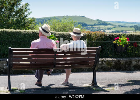 Anziani pensionati giovane relax su una panchina nel parco prendendo in considerazione di Blackmore Vale in shaftesbury, Dorset Foto Stock