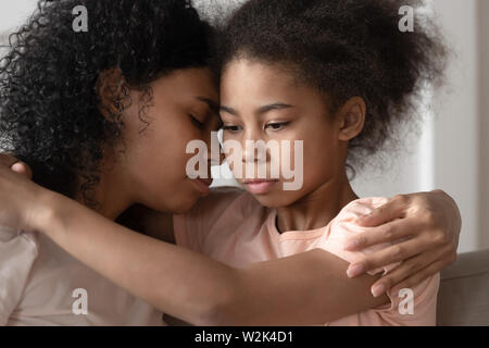 Riflessivo African American kid figlia abbracciando la mamma coccole di incollaggio Foto Stock