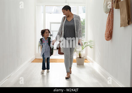 Ragazza con sua madre camminare insieme mano nella mano nei pressi di Porta a casa Foto Stock