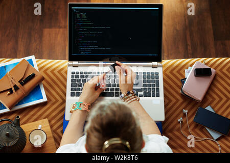 Vista superiore di eleganti donna seduta sul divano del soggiorno moderno sviluppo di software e la lucidatura delle unghie. Foto Stock