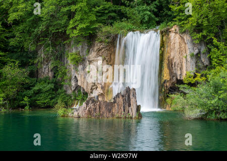 Crystal Clear, acqua pura e correre verso il basso le rocce di muschio in un bellissimo colore azzurro lago presso il Parco Nazionale dei Laghi di Plitvice in Croazia Foto Stock