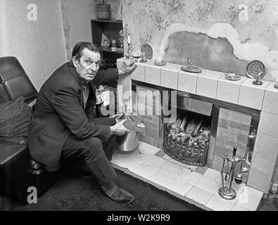 Uomo anziano che cerca di tenersi al caldo con un fuoco aperto nel North Yorkshire, Gran Bretagna 1985. bollette del carburante costi di riscaldamento rimborso carburante invernale Foto Stock