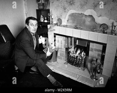 Uomo anziano che cerca di tenersi al caldo con un fuoco aperto nel North Yorkshire, Gran Bretagna 1985. bollette del carburante costi di riscaldamento rimborso carburante invernale Foto Stock