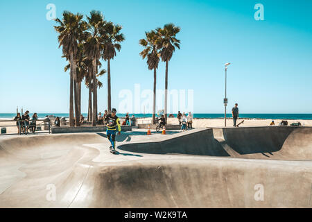 La spiaggia di Venice, California, Stati Uniti d'America - 10 Aprile 2019: un guidatore di skateboard salta con il suo pattino ed eseguire un trick Foto Stock