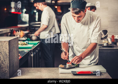 Maschio di cuochi prepara sushi al ristorante cucina Foto Stock