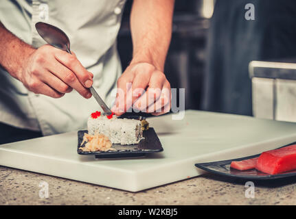 Maschio di cuochi prepara sushi al ristorante cucina Foto Stock
