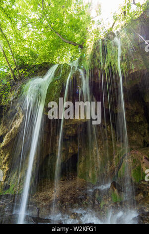 Vista retroilluminato di pura acqua fresca correre verso il basso una roccia nel profondo della foresta del Parco Nazionale dei Laghi di Plitvice in Croazia Foto Stock