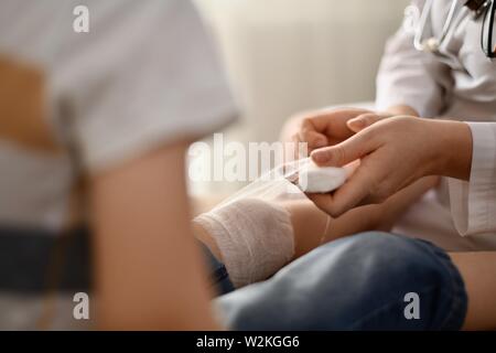 Il medico si siede sul bordo del letto accanto a un sorridente, fingendo bambino dormiente. Foto Stock