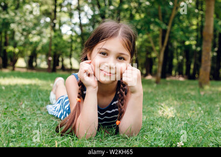 Carino bambina posa sul verde erba fresca in estate park Foto Stock