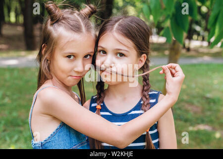 Due bambine divertirsi nel parco nella soleggiata giornata estiva Foto Stock