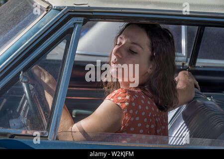 Un attrrative giovane donna seduta in una macchina Foto Stock