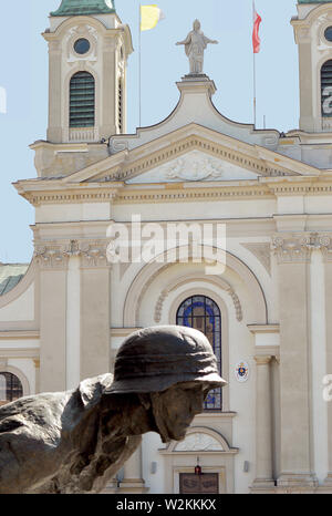 Varsavia, Polonia - 16 Aprile 2019: figura dall'Insurrezione di Varsavia monumento spicca contro la Cattedrale di campo dell'Esercito Polacco in Krasinski Square Foto Stock