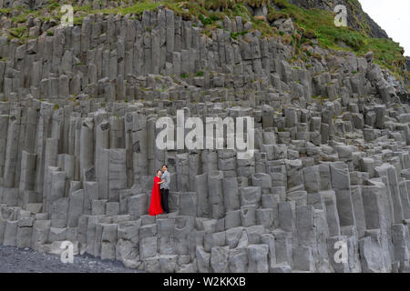 Un matrimonio giovane avente le foto scattate su colonne di basalto Reynisfjara sulla spiaggia di sabbia nera, sud dell'Islanda. Foto Stock