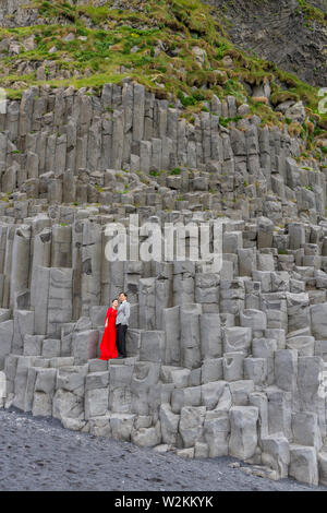 Un matrimonio giovane avente le foto scattate su colonne di basalto Reynisfjara sulla spiaggia di sabbia nera, sud dell'Islanda. Foto Stock