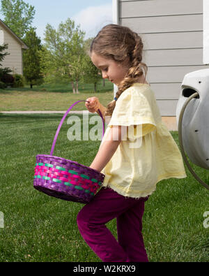 5 anno vecchia ragazza caucasica controlla le sue uova nel suo uovo di pasqua basket all'aperto. Stati Uniti d'America. Foto Stock