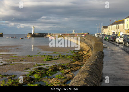 Sole serale a Donaghadee Harbour lights fino barche, faro e porto dopo un nuvole grigie e pesanti e doccia. Foto Stock