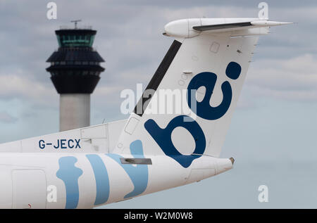 Il tailfin di un aereo di linea Flybe rullaggio lungo la pista di fronte alla torre di controllo dell'aeroporto di Manchester. Foto Stock