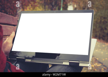 Un uomo sta lavorando con computer portatile presso park. outdoor, schermata vuota per background. tablet trasformatore in una mano d'uomo Foto Stock