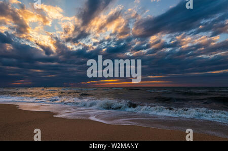 Spiaggia con le onde a tramonto colorato Foto Stock