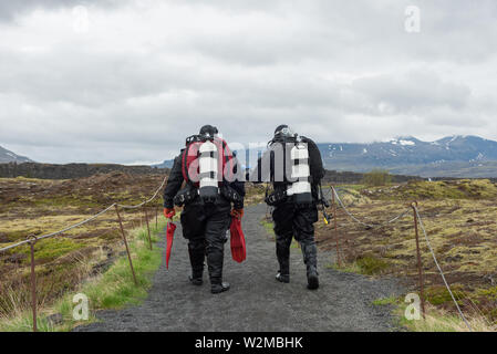 SILFRA, Islanda - 20 Maggio 2019: subacquei camminando su un percorso dopo una immersione Silfra rift, il luogo dove Eurasian e l'Americano targa tettonica Foto Stock