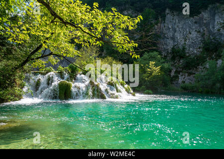 Impetuose cascate di acqua verso il basso le naturali barriere in cristallo chiaro e di colore azzurro lago Gavanovac presso il Parco Nazionale dei Laghi di Plitvice, Croazia Foto Stock