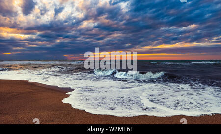 Spiaggia con le onde a tramonto colorato Foto Stock