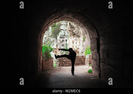 Silhouette di un uomo a praticare il karate mosse e tecniche in un buio del tunnel Foto Stock