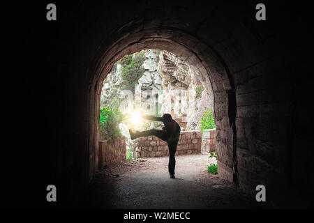 Silhouette di un uomo a praticare il karate si muove in un buio del tunnel Foto Stock