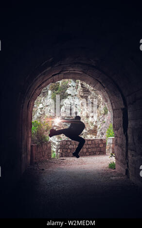 Silhouette di un uomo salta durante la pratica del karate in un buio del tunnel Foto Stock