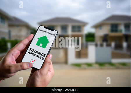 Finanziare l'accordo di prestito e la chiave di casa mutuo ipotecario approvazione sul telefono cellulare in una casa Foto Stock