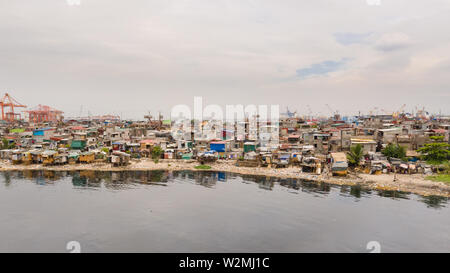 Baraccopoli di Manila vicino al porto. Case di abitanti poveri. Un sacco di immondizia in acqua, Filippine, vista dall'alto. Foto Stock