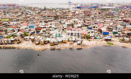 Baraccopoli di Manila vicino al porto. Case di abitanti poveri. Un sacco di immondizia in acqua, Filippine, vista dall'alto. Foto Stock