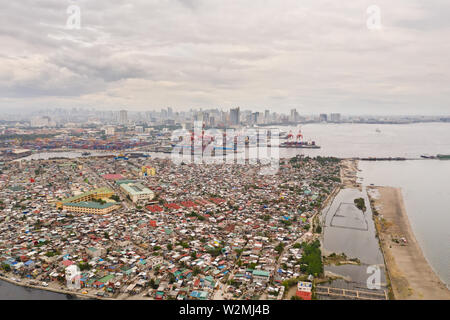 Porto di Manila nelle Filippine. Porto di Mare con gru di carico. Paesaggio con aree povere e business center nella distanza, vista da sopra. Metropoli asiatica. Foto Stock