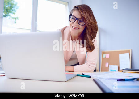 Donna felice lavorando sul suo computer portatile in ufficio Foto Stock