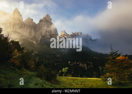 Moody paesaggio panoramico nel Monestir de Montserrat regione vicino a Barcellona Spagna con frastagliate pinnacoli di montagna che si eleva al di sopra di una lussureggiante valle boscosa e Foto Stock