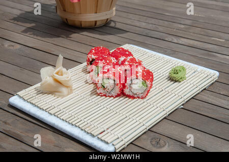 Close-up di sushi e panini al ristorante Cucina. Giapponese cucina tradizionale. California sushi rotoli sul supporto di bambù su sfondo di legno Foto Stock