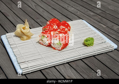 Close-up di sushi e panini al ristorante Cucina. Giapponese cucina tradizionale. California sushi rotoli sul supporto di bambù su sfondo di legno Foto Stock