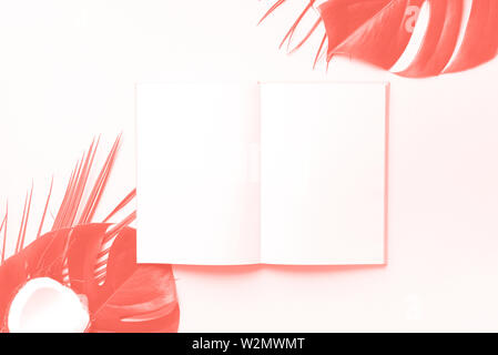 Green monstera, foglie di palma, di cocco, di notebook su corallo trendy colore di sfondo. Femmina scrittore blog workspace, torna al concetto di scuola. Lay piatto. A Foto Stock