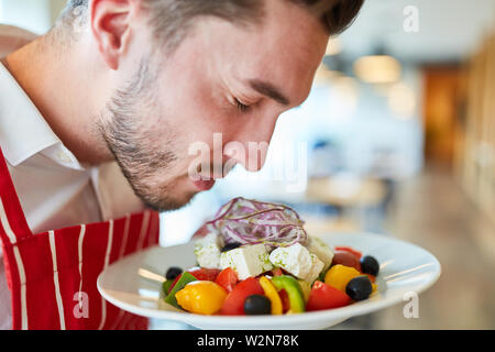 Cameriere servire fresca e gustosa insalata greca nel ristorante Foto Stock