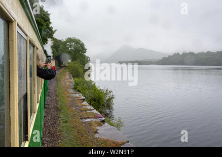 Llanberis Lake e montagne di Snowdonia in luce pioggia visto dal lento movimento del treno a vapore - 1 Foto Stock