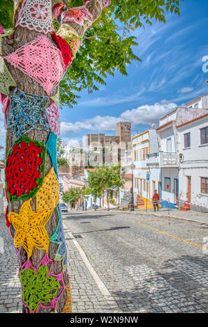 Mertola, Portogallo - 18 Maggio 2019: alberi decorati con colorate uncinetto patchwork in una vacanza nella città di Mertola, una bellissima città del Po Foto Stock