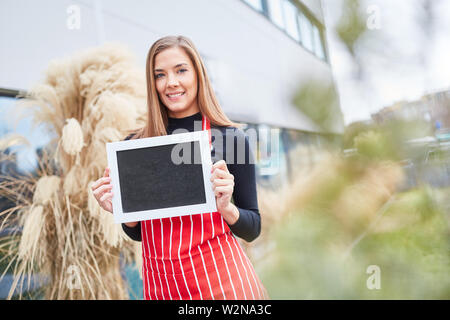 Cameriera nella parte anteriore del ristorante conserva lavagna vuota nelle sue mani Foto Stock