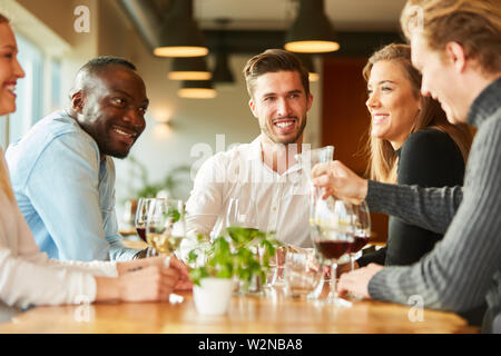 Gruppo di amici incontra per la piccola conversazione davanti a un bicchiere di vino nel ristorante Foto Stock