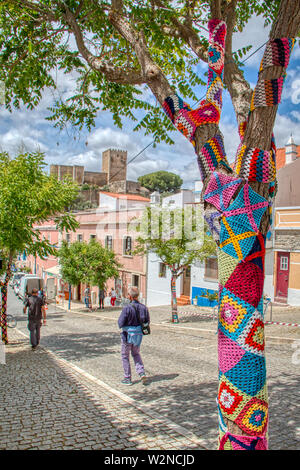 Mertola, Portogallo - 18 Maggio 2019: alberi decorati con colorate uncinetto patchwork in una vacanza nella città di Mertola, una bellissima città del Po Foto Stock