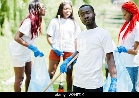 Gruppo di felice africana di volontari con sacchi della spazzatura area di pulizia nel parco. Africa volontariato, carità, persone e concetto di ecologia. Foto Stock