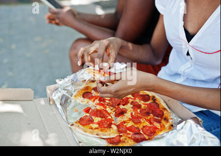 Mani di African American donna con la pizza. Foto Stock